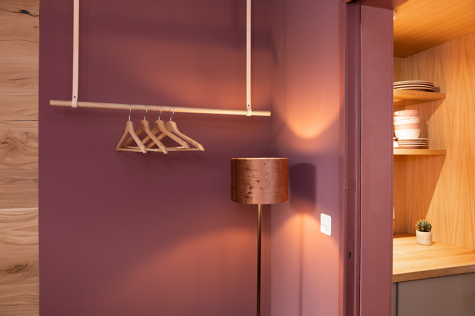Garderobe: Detail hängende Kleiderstange mit Bügeln und leuchtender Stehlampe